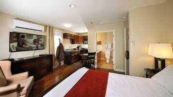 Een hotelkamer met een bed, televisie, bureau, stoel, kitchenette en een badkamer.