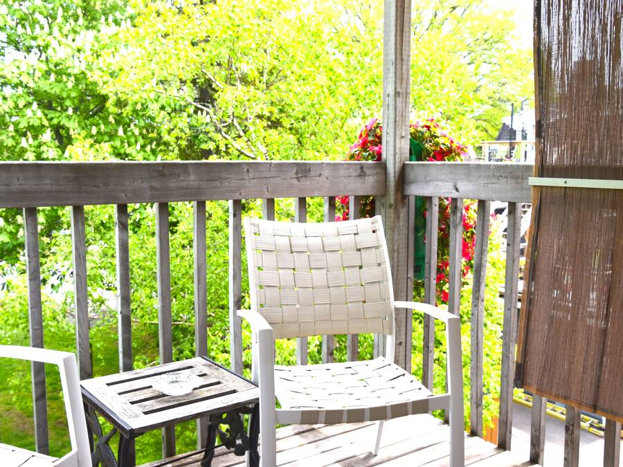 A wooden deck with a white wicker chair and a small table.