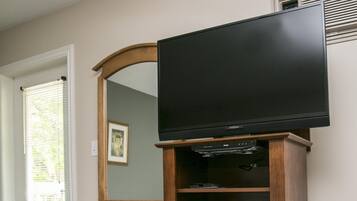 Een kamer met een houten dressoir, een televisie erboven en een witte koelkast.