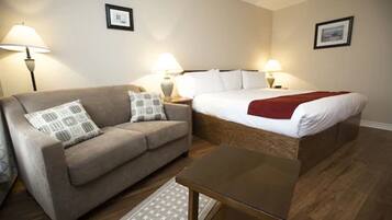 A hotel room with a bed, a sofa, a table, and two lamps.