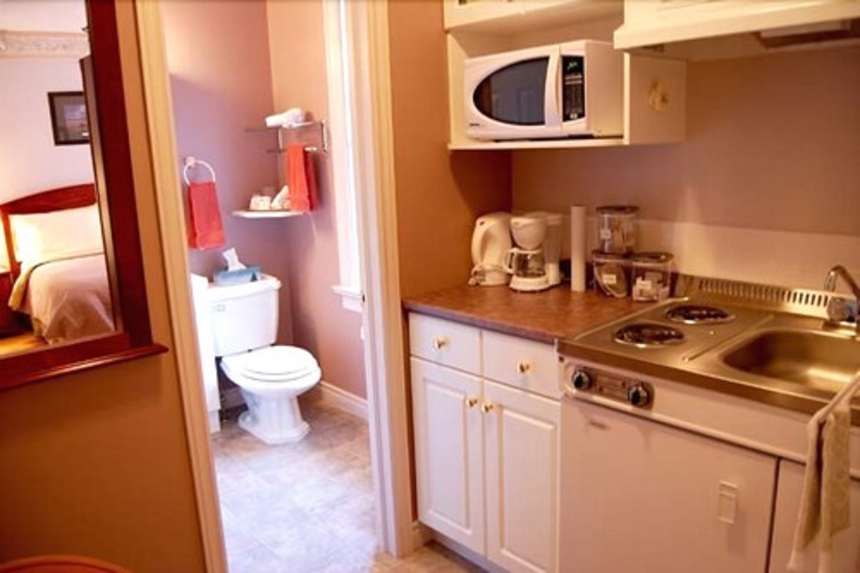 A compact kitchen with a microwave, coffee maker, and sink.