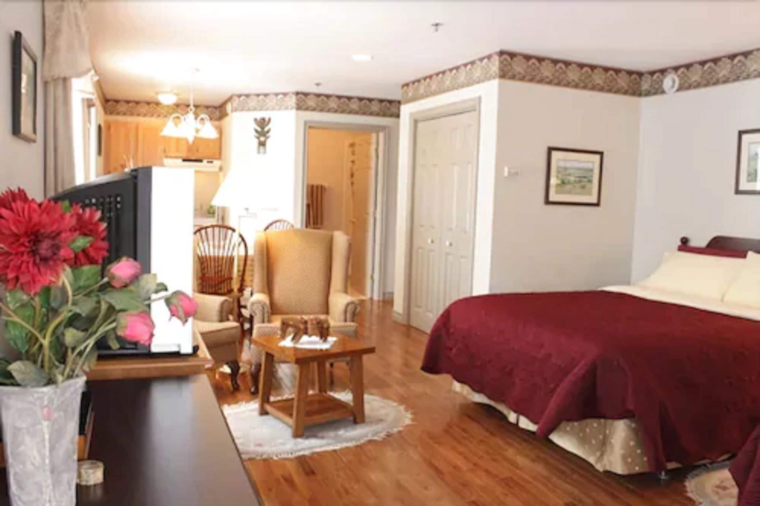 A bedroom with a bed, a chair, a table, and a TV.