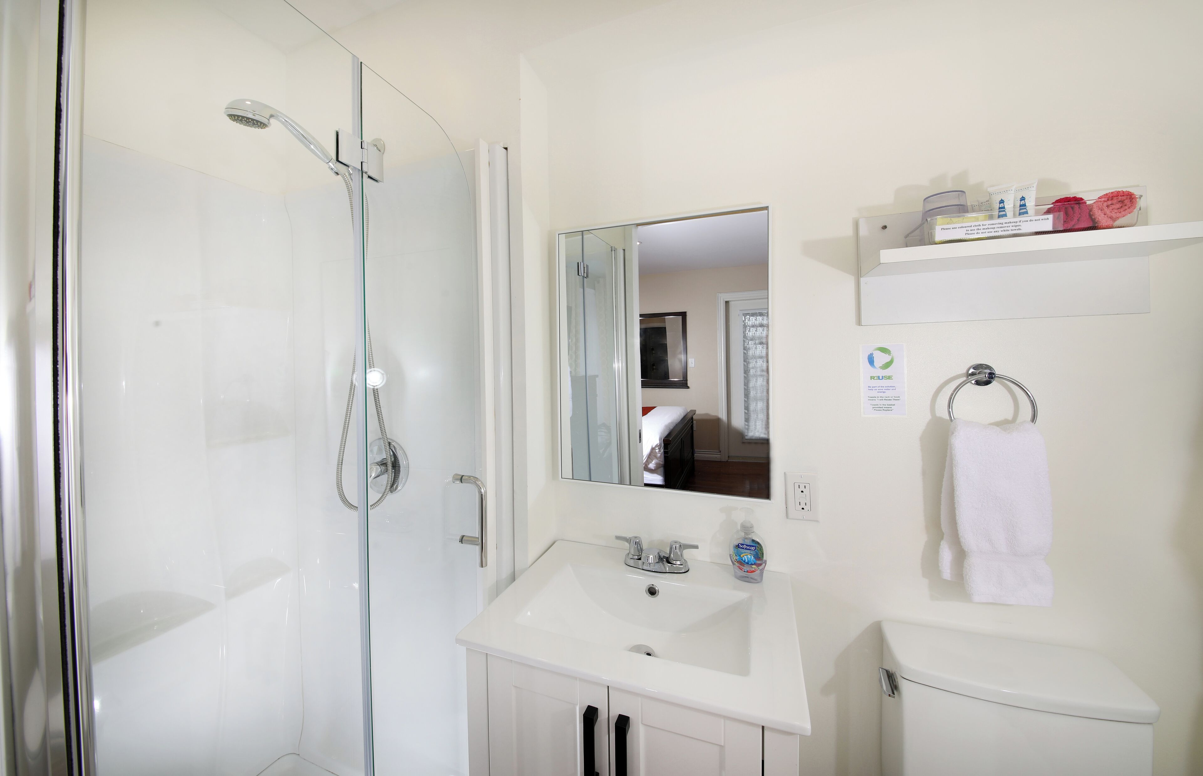 Ein modernes Badezimmer mit Duschkabine aus Glas, einem weißen Waschbecken und einer Toilette.