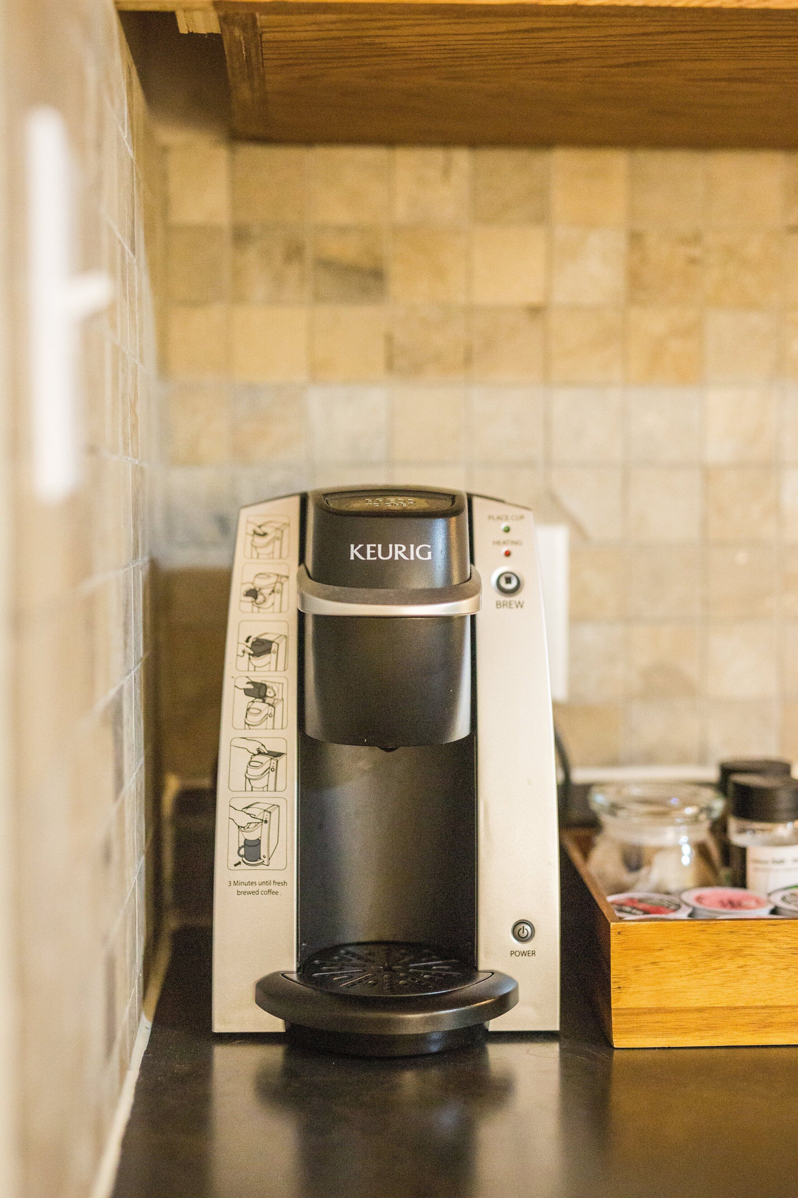 A Keurig coffee maker on a kitchen counter with a tiled backsplash.