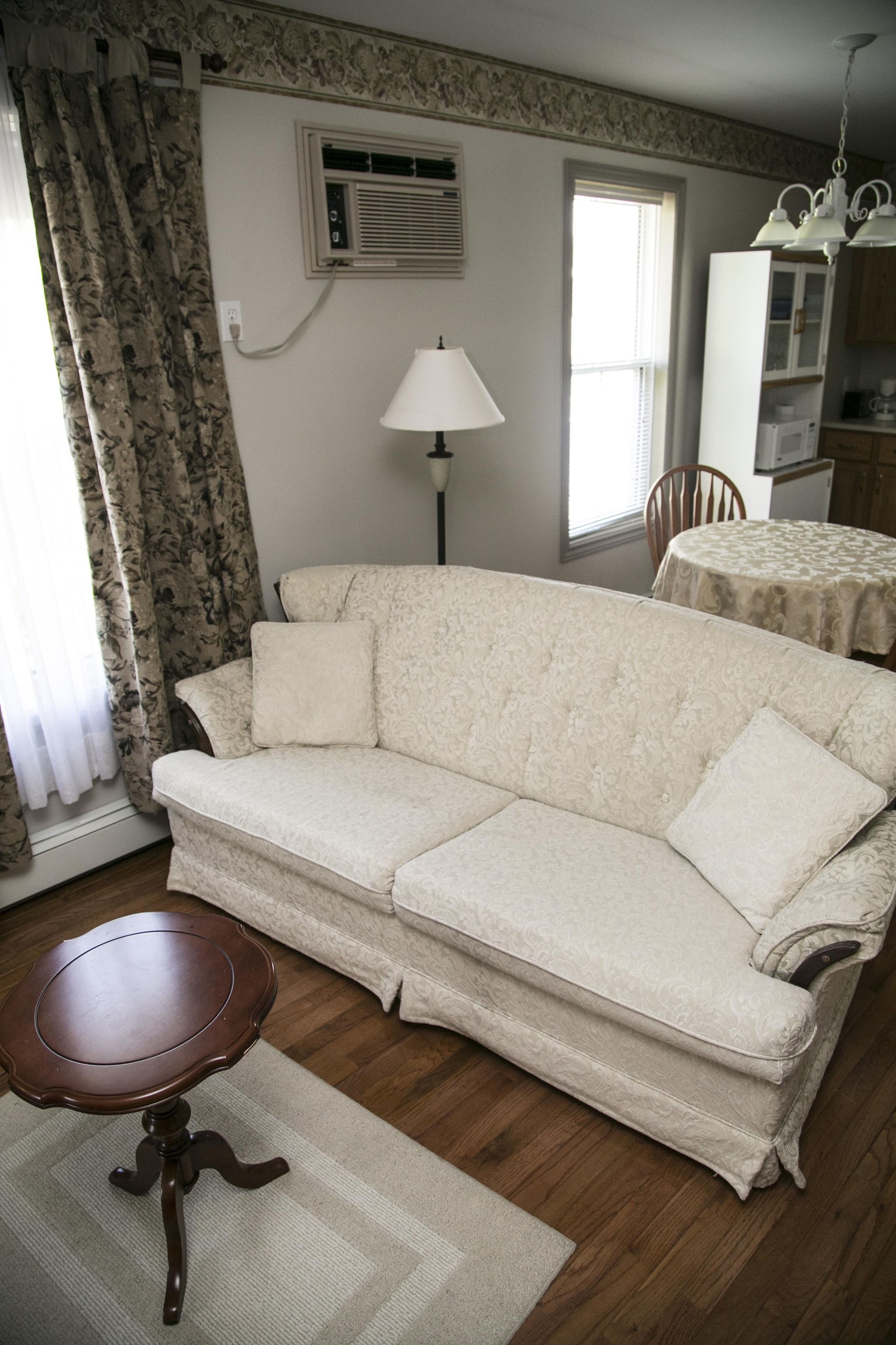 A living room with a beige sofa, a small wooden table, and a lamp.