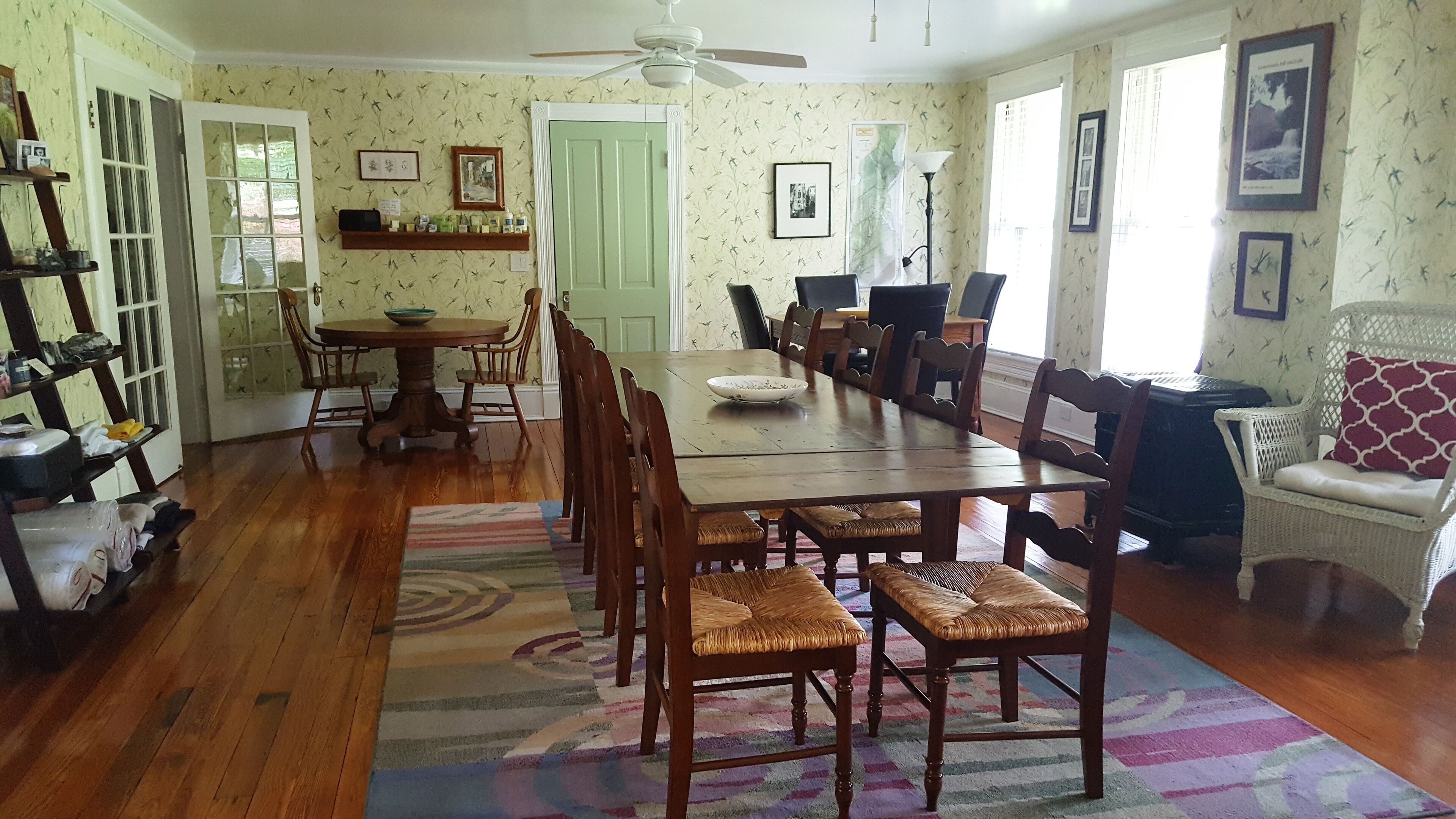 Ein Esszimmer mit einem langen Holztisch, Stühlen und einem gemusterten Teppich.