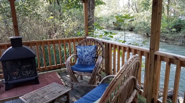 A wooden deck with a rustic chair and a built-in fireplace.