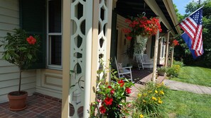 A porch with a white lattice, a potted plant, a chair, and an American flag.