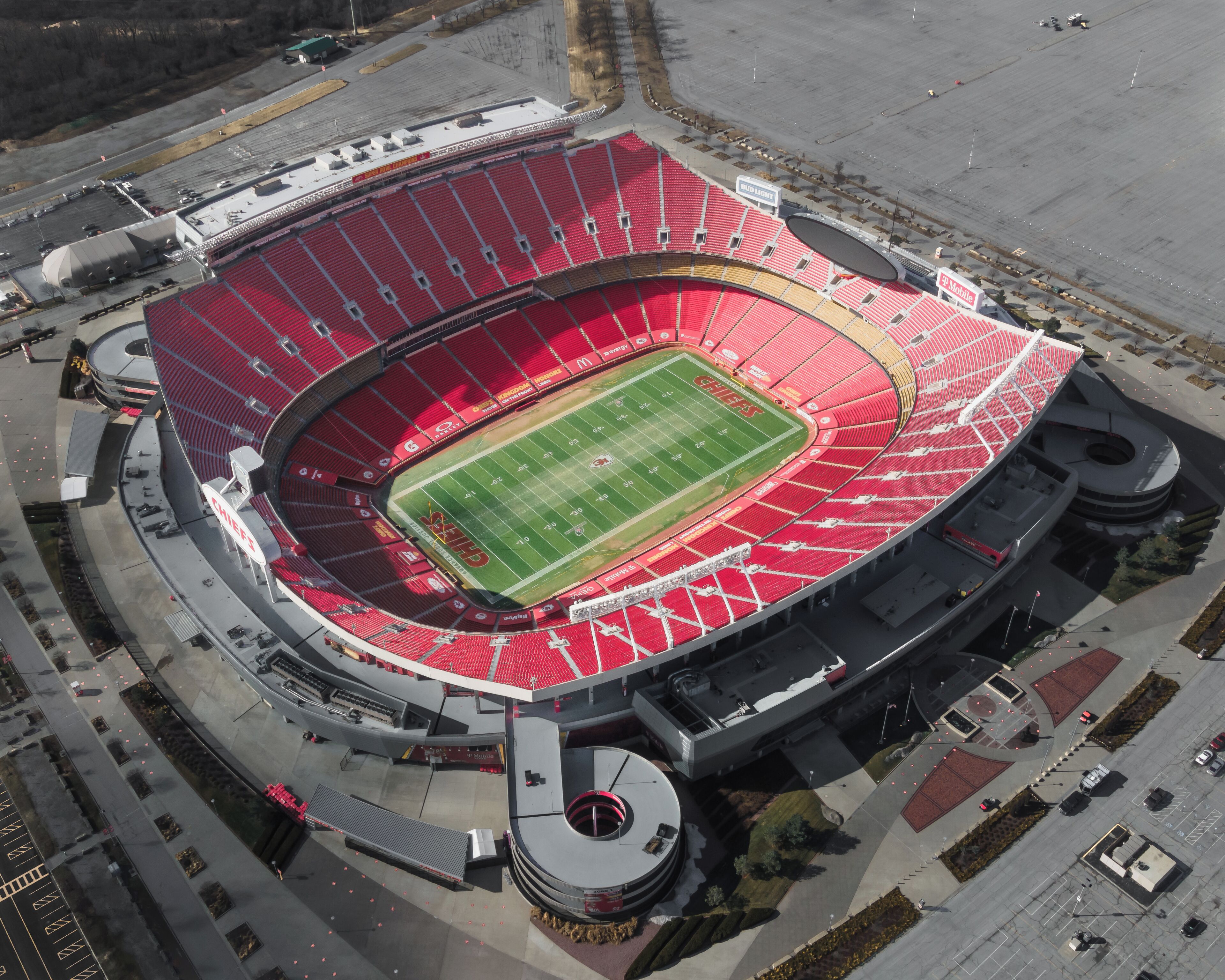 Vista aérea de un estadio con cancha de fútbol, asientos en niveles escalonados y una estructura circular en el centro.