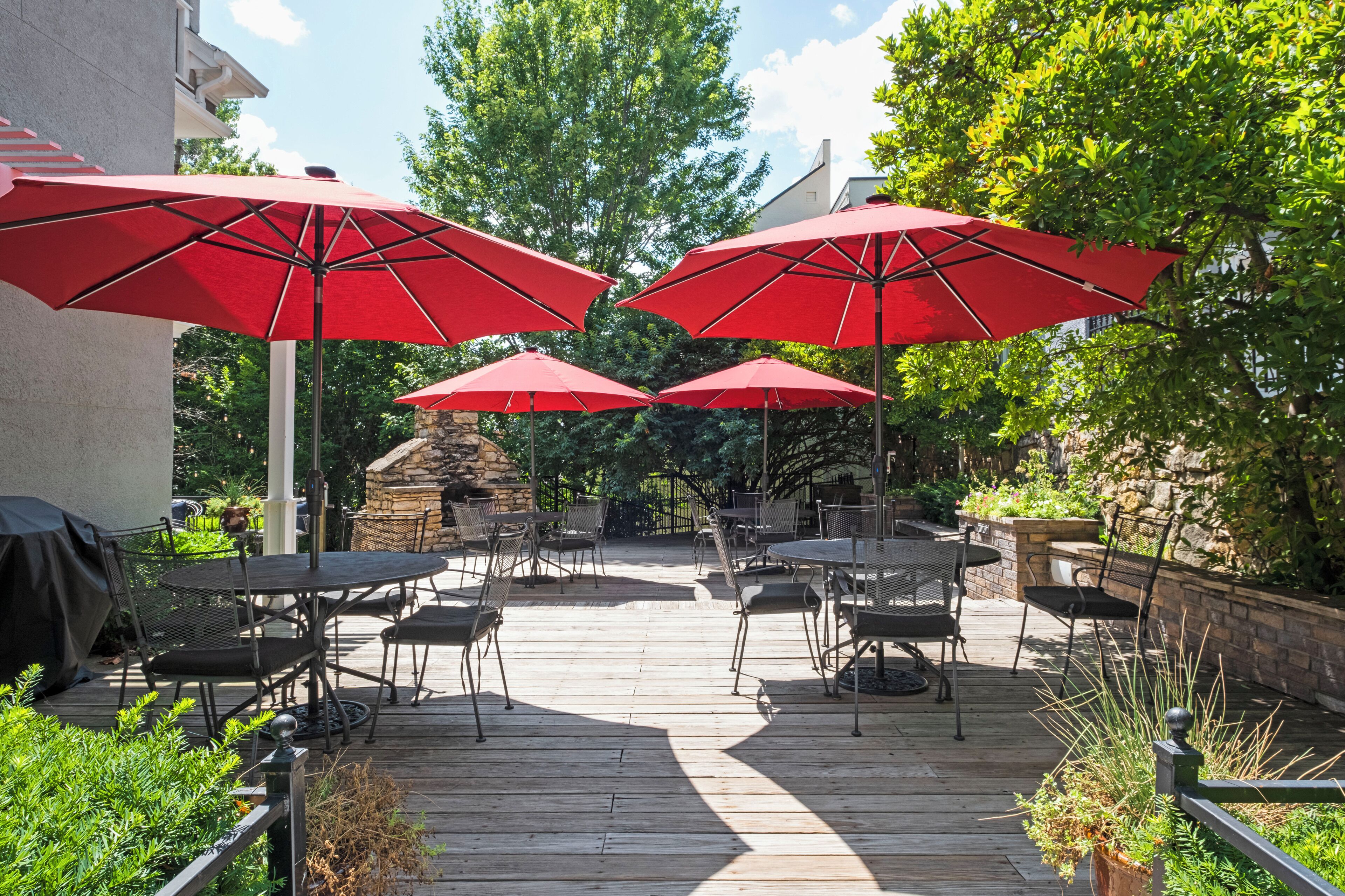 A patio area with multiple red umbrellas, outdoor tables, and chairs.
