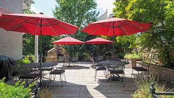 A patio area with multiple red umbrellas, outdoor tables, and chairs.