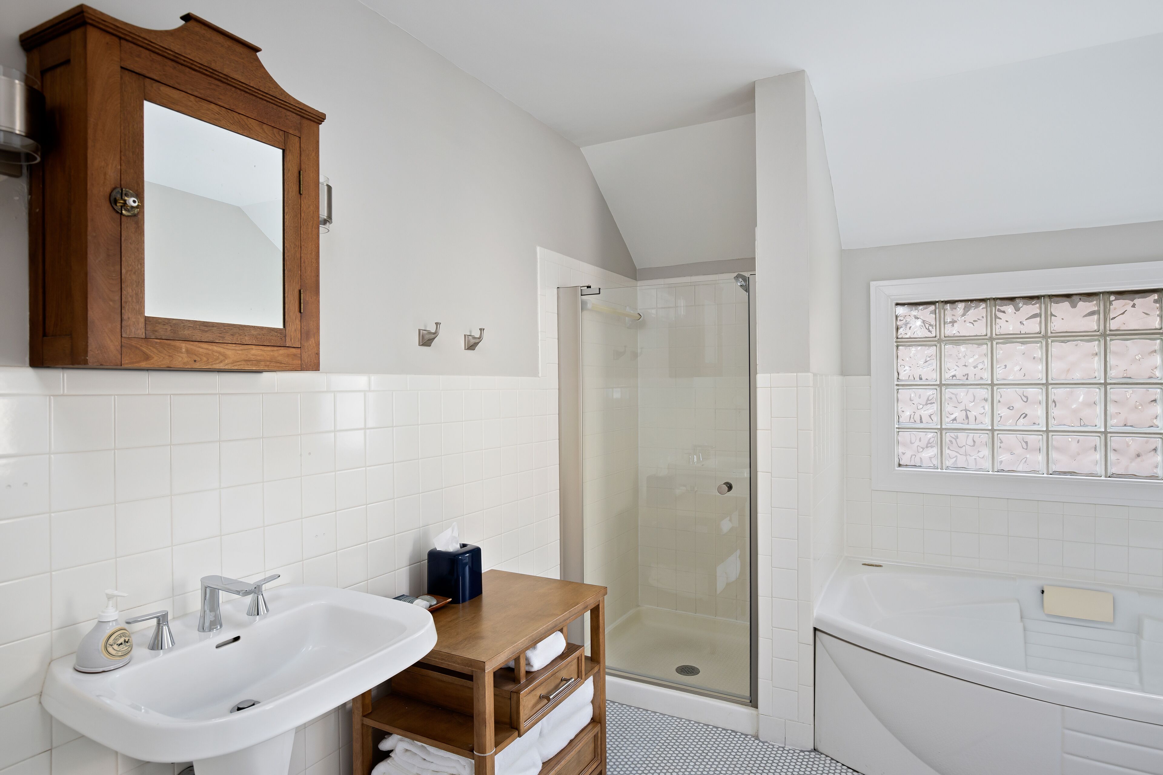 A bathroom with a wooden cabinet, a sink, a glass shower enclosure, and a bathtub.