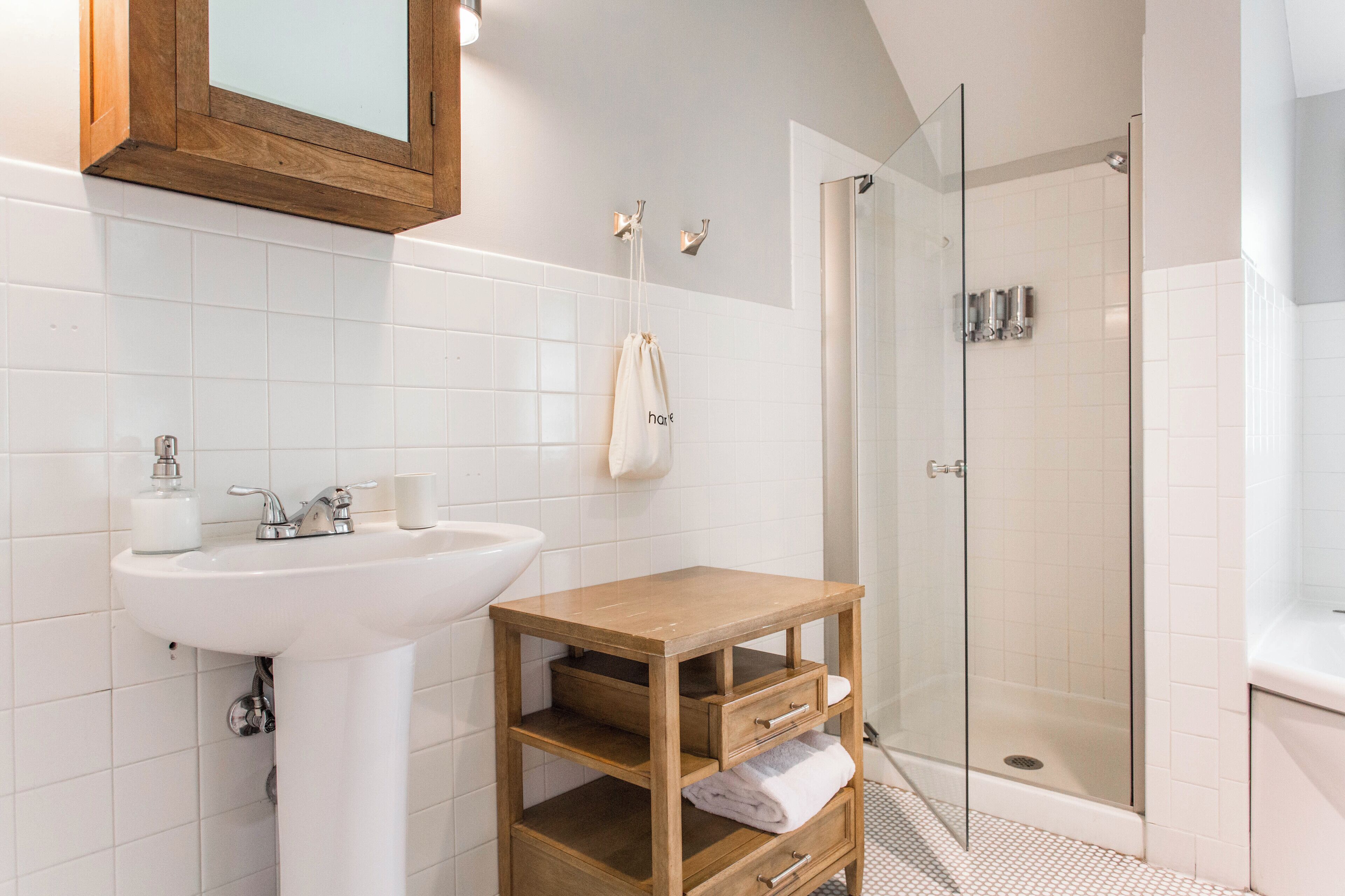 A modern bathroom with a white sink, wooden vanity, and a glass shower enclosure.