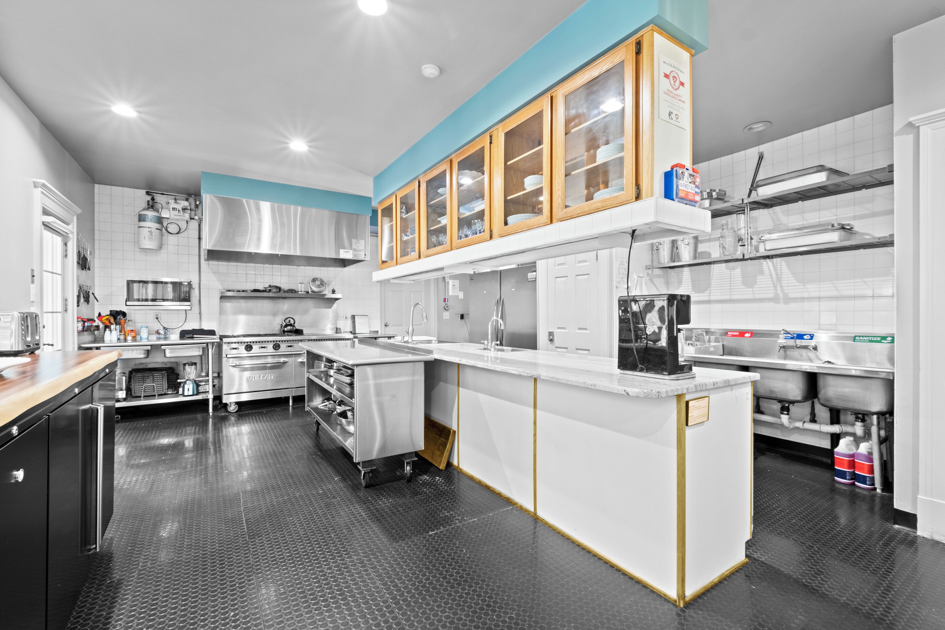 A modern kitchen with stainless steel appliances, a central island, and a blue accent wall.
