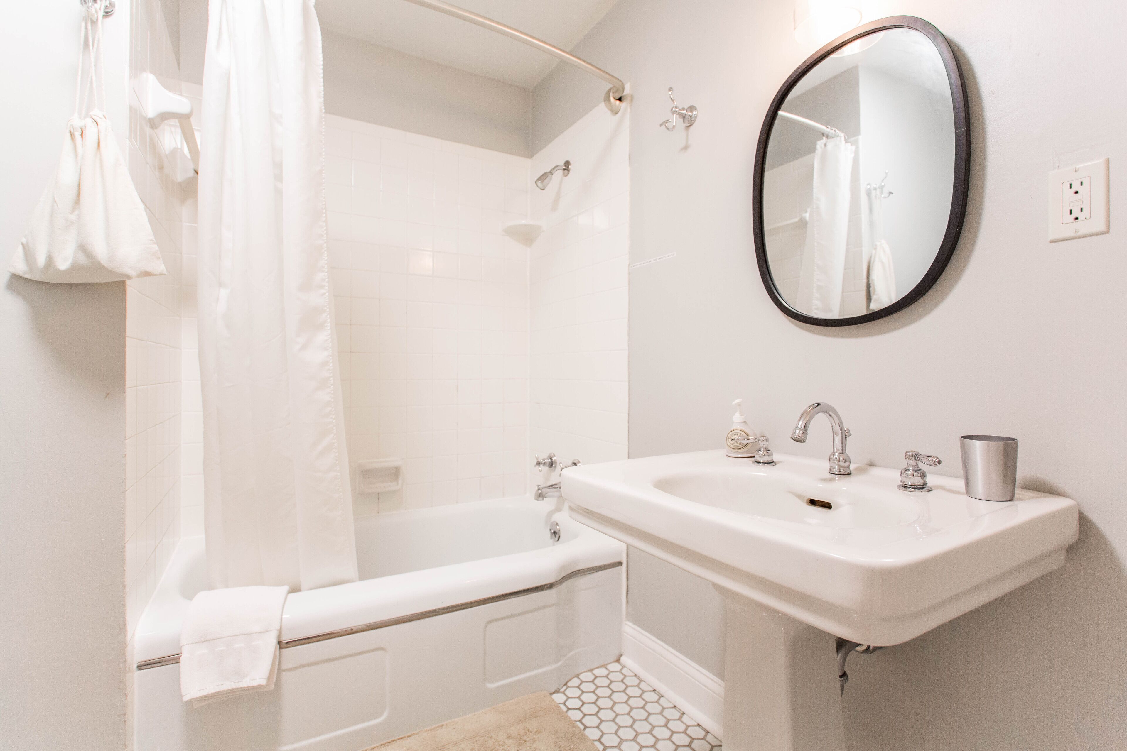 Un baño con bañera, lavamanos, espejo y cortina de ducha.