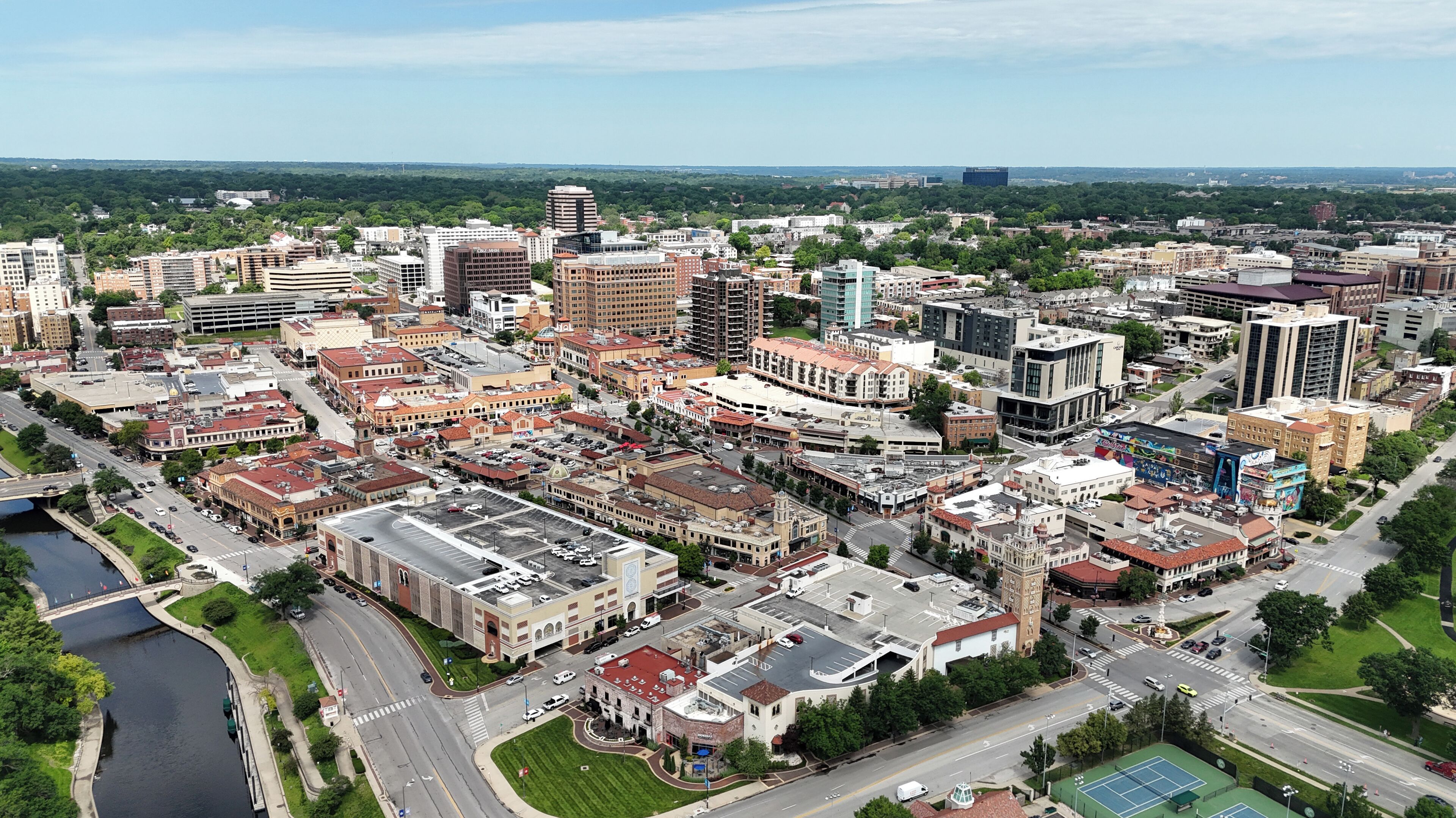 An aerial view of a cityscape with a mix of historic and modern buildings, a river, and a sports complex.