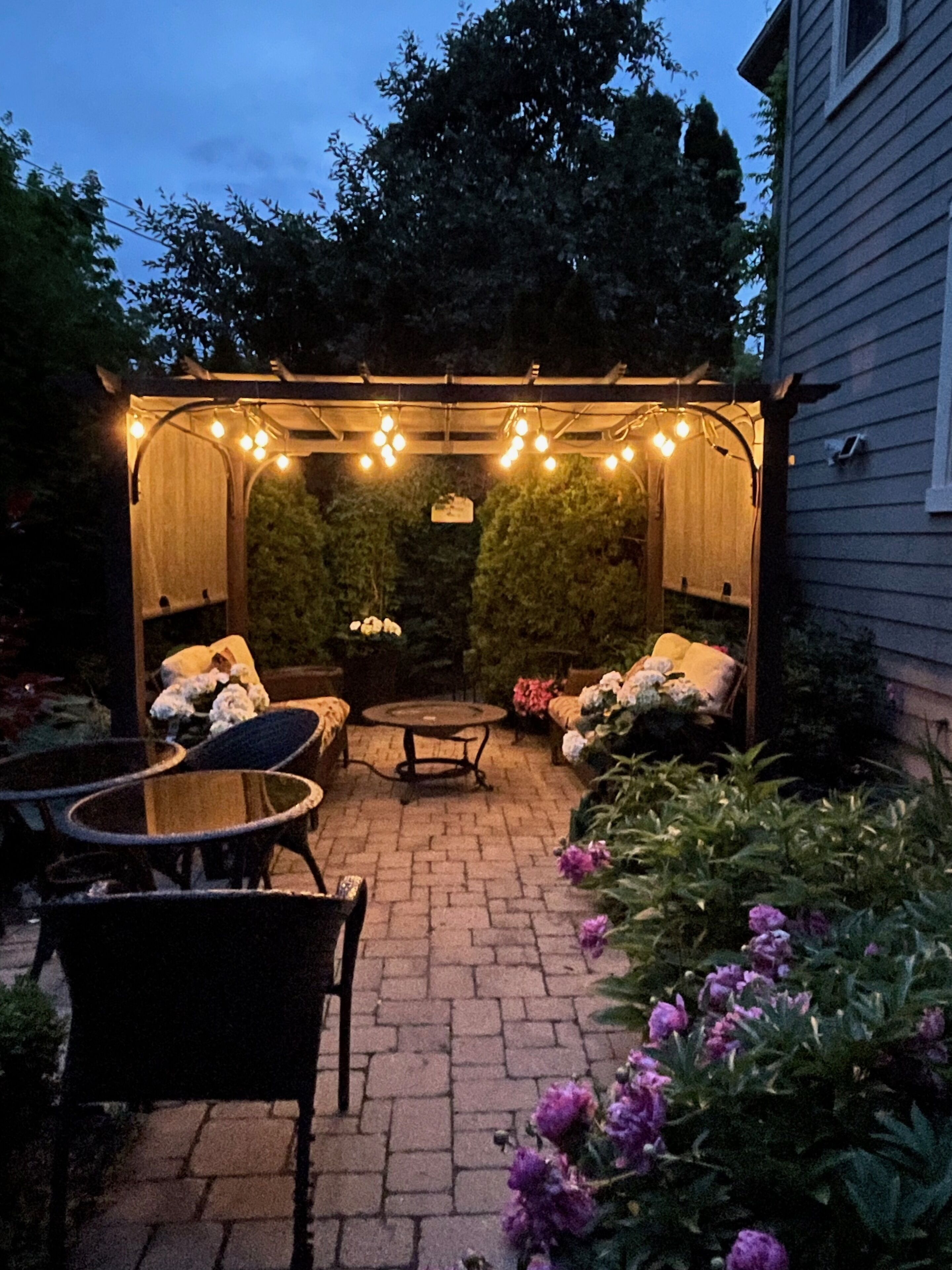 Un patio con pérgola, mobiliario exterior y suelo de ladrillo.