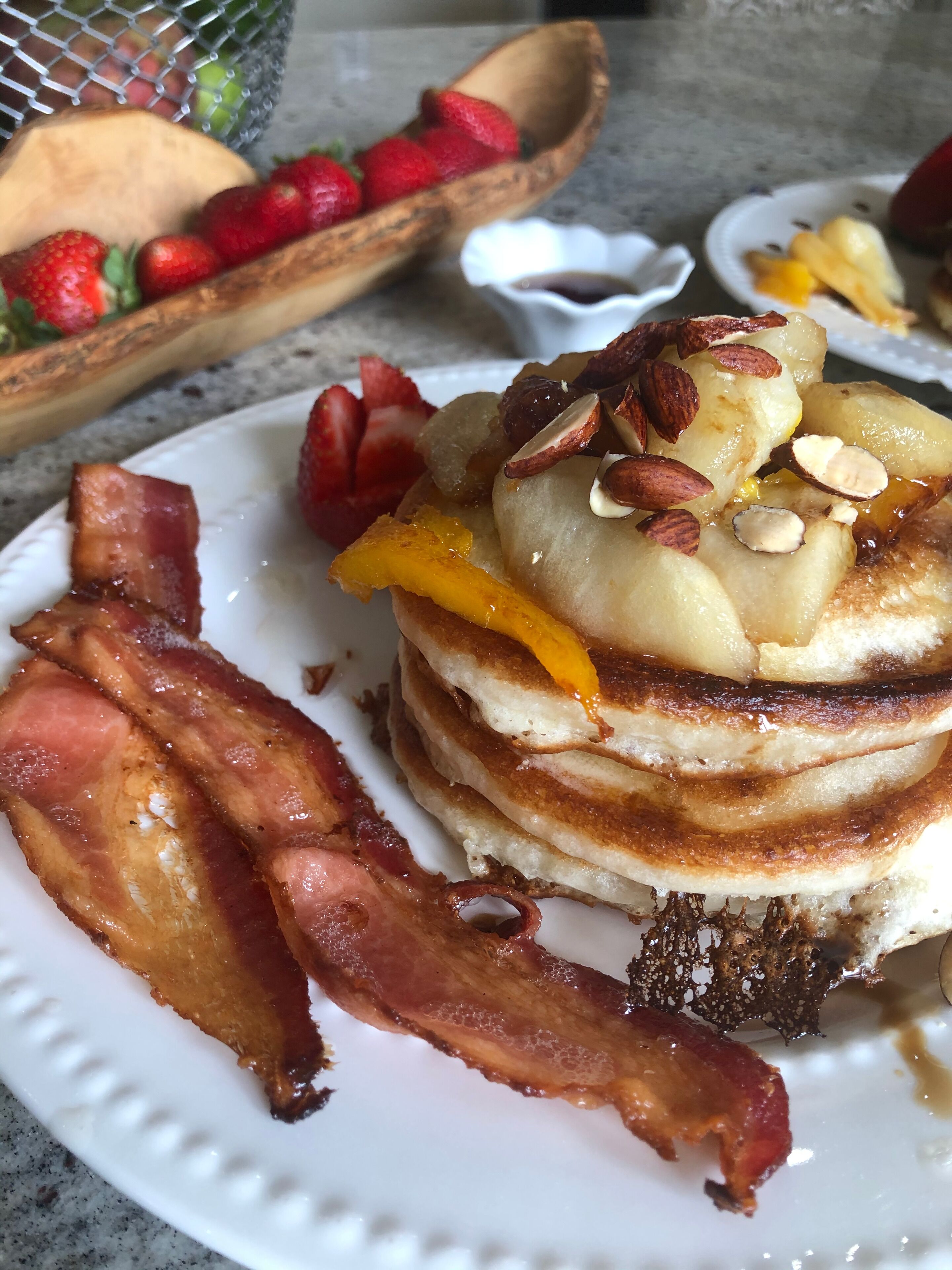 A plate of pancakes with bacon and fruit toppings.