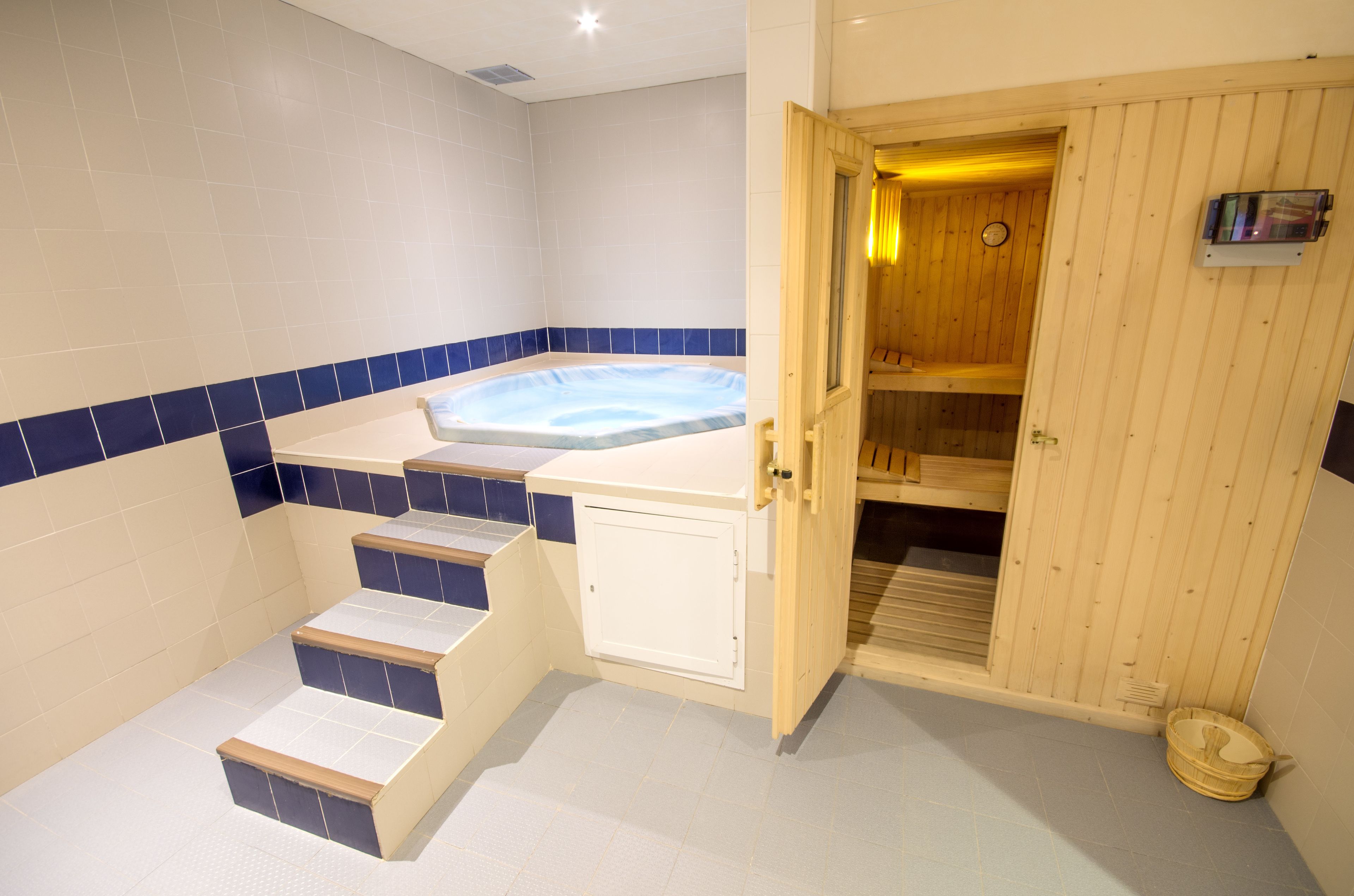 Un área de spa con un jacuzzi, escalones de madera y una puerta de madera que da a una sauna.