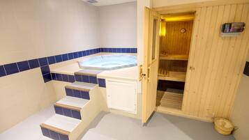 Un área de spa con un jacuzzi, escalones de madera y una puerta de madera que da a una sauna.