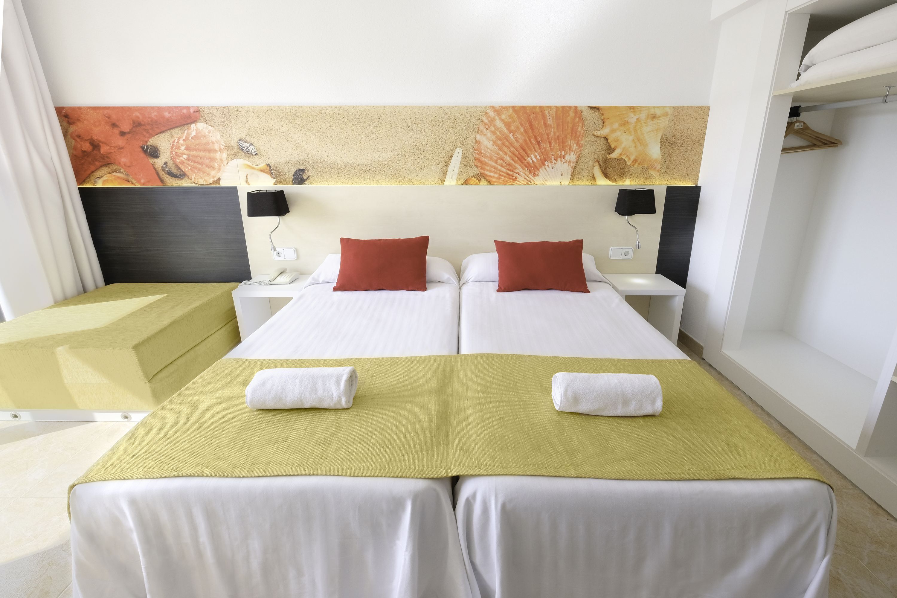Een hotelkamer met twee bedden, een groot schilderij aan de muur en een nachtkastje met een lamp.