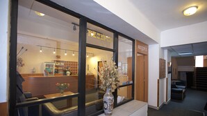 A reception area with a vase of flowers, a reception desk, and a sign that reads "RECEPTION". - Hotel Olga (Prague)