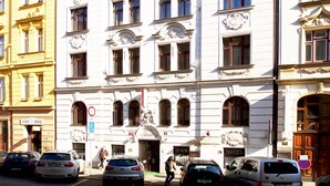 A multi-story building with a classic architectural style, featuring a central entrance with a decorative archway and a sign indicating a hotel. - Hotel Olga (Prague)