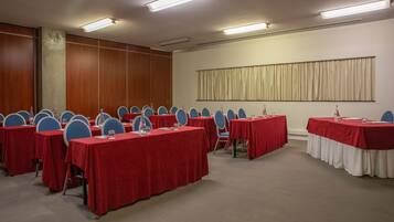 Une salle de conférence dotée de plusieurs tables et chaises, ainsi que de bouteilles d’eau et de plaques nominatives.