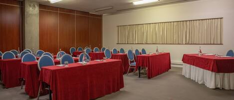 A conference room with multiple tables and chairs, equipped with water bottles and nameplates.