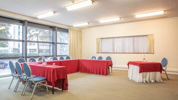 Ein Konferenzraum mit langem Tisch und Stühlen, großen Fenstern und Ausblick nach draußen.