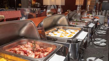 A buffet with various food options including bacon, eggs, and other dishes.