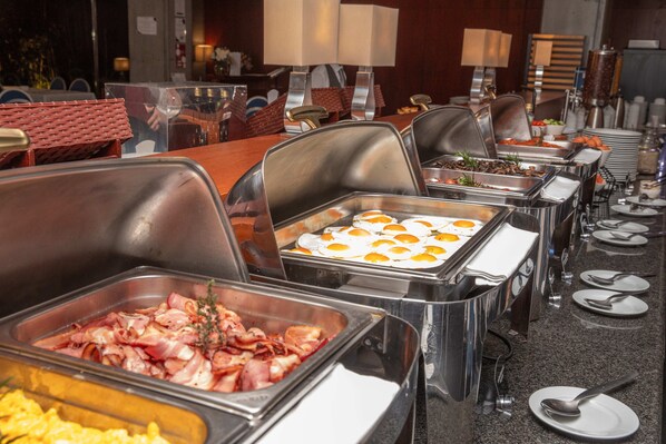 Un buffet proposant une variété de plats, notamment du bacon, des œufs et d’autres mets.