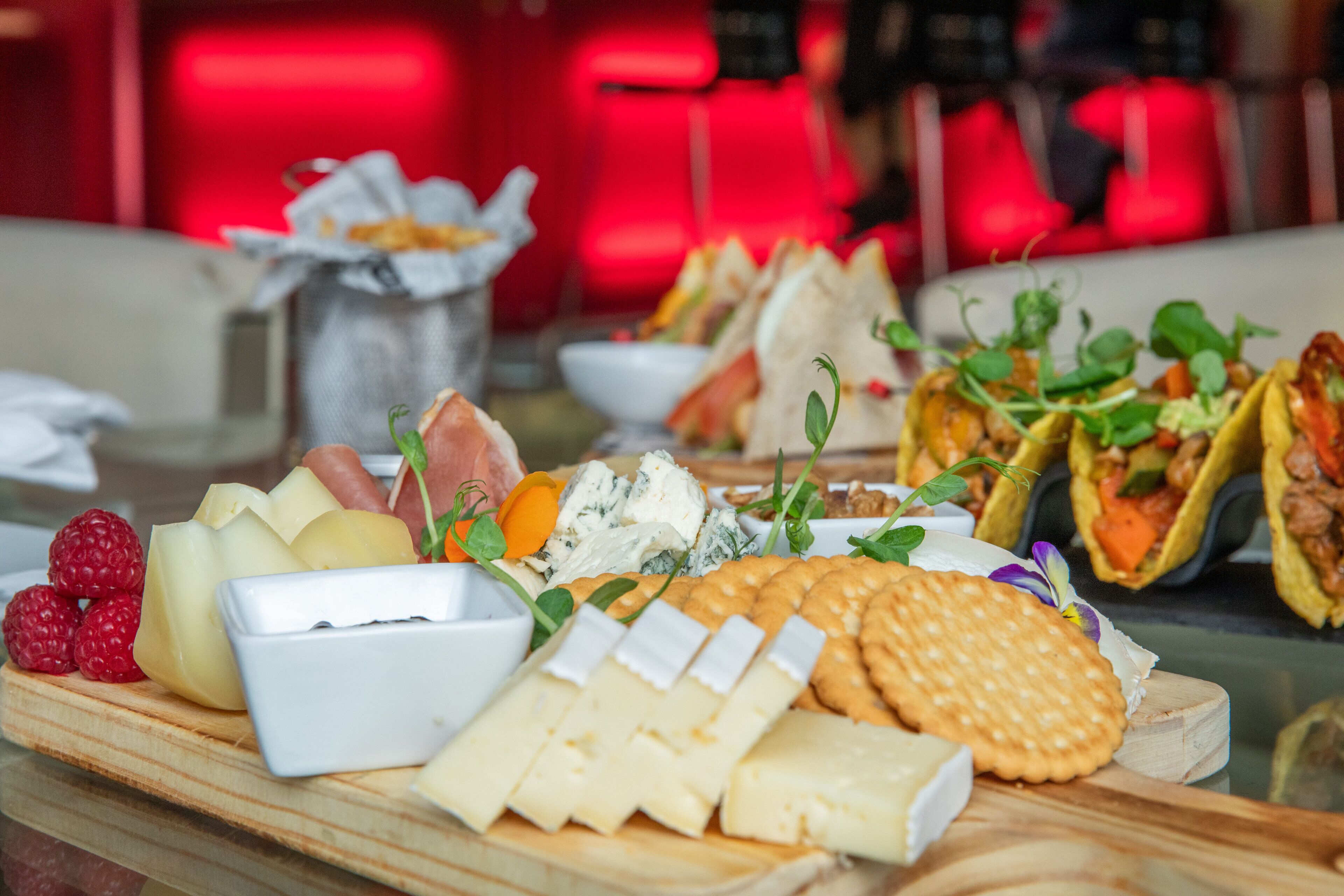 A variety of cheeses, fruits, and crackers on a wooden board.