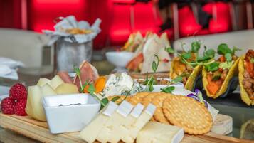 A variety of cheeses, fruits, and crackers on a wooden board.