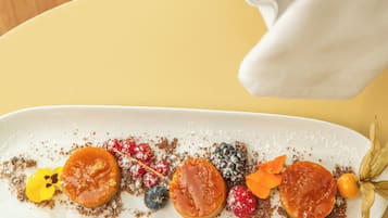 Un plato de postre con varias frutas y una botella de vino.
