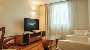 Una sala de estar moderna con un televisor de pantalla plana, una mesa de centro de vidrio y sofás de cuero blanco.