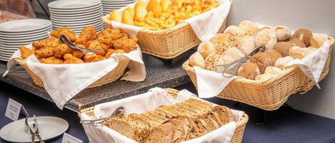 A buffet with various bread and pastries displayed in baskets.