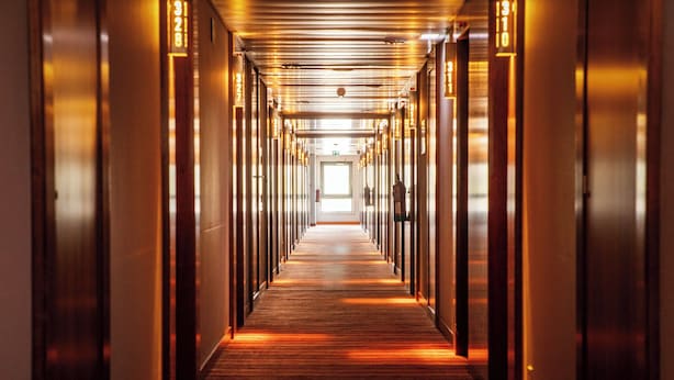 A long, narrow hallway with doors on both sides, leading to a bright exit at the end. - VIP Executive Santa Iria Hotel (Loures)