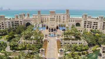 A large hotel with multiple floors, a central courtyard, and a view of the sea.