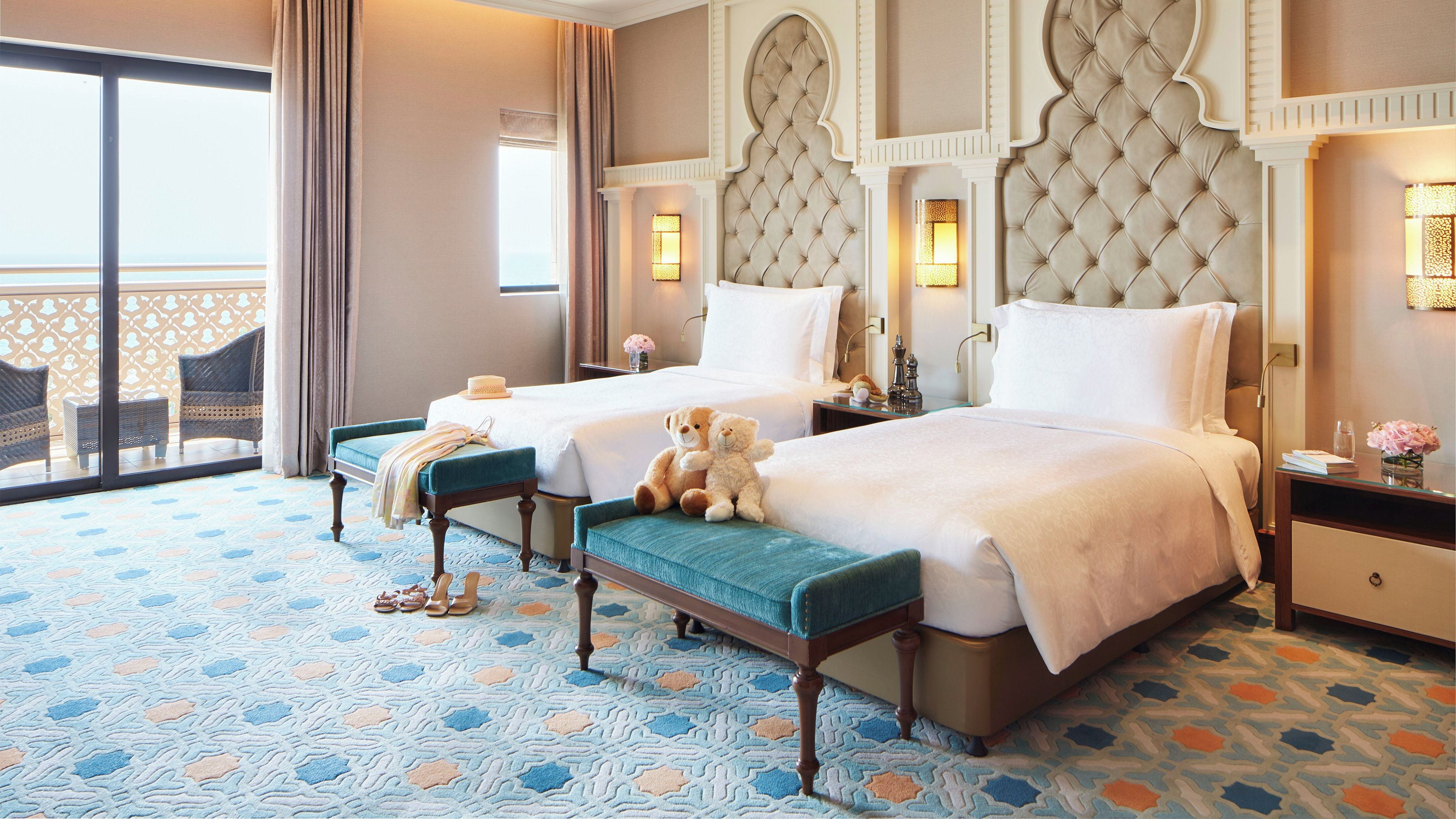 Une chambre d’hôtel avec deux lits, un balcon et un sol à motifs.