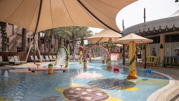 Relax by the pool with a water slide and jets, surrounded by lounge chairs and shaded seating areas.