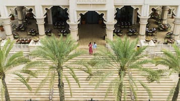A courtyard with palm trees, outdoor seating, and a central entrance.