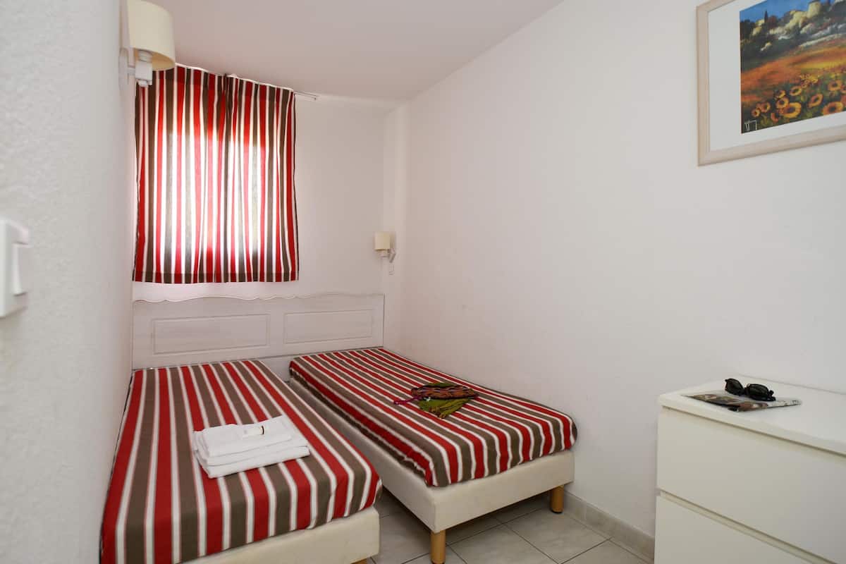 Ein Zimmer mit zwei Betten, einem Schreibtisch, einer Lampe und einem Bild an der Wand.