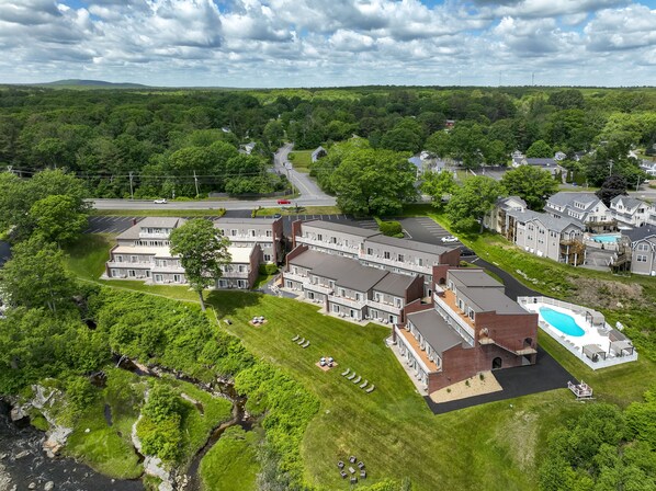 An aerial view of a residential area with a large building complex, a swimming pool, and a road.