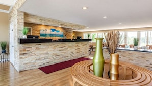 A reception area with a stone wall, a painting of a beach, and a reception desk. - Ogunquit River Inn & Suites (Ogunquit)