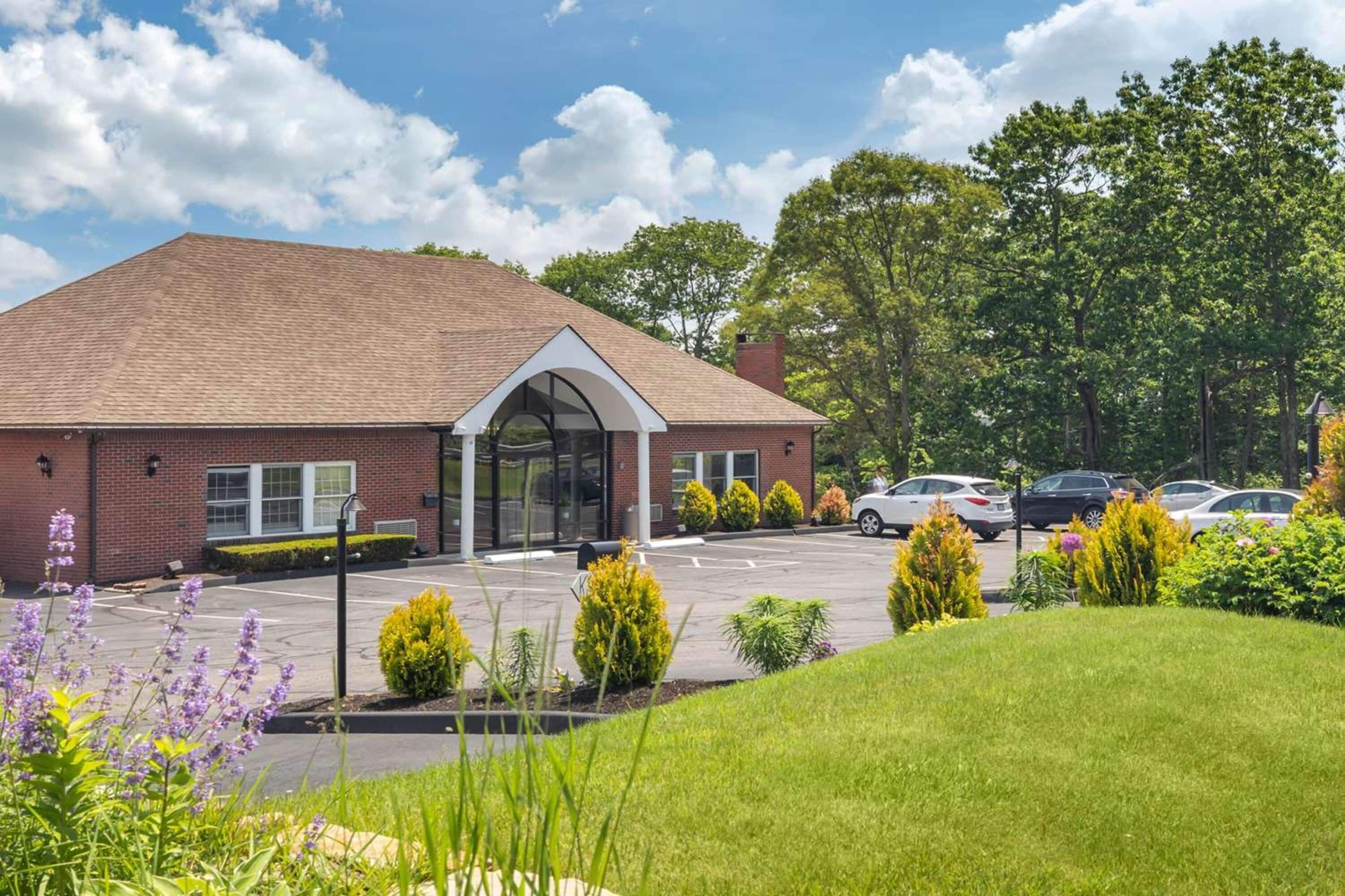 A brick building with a large entrance and a parking lot.