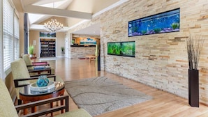 A spacious living area with a large aquarium, comfortable seating, and a modern kitchen in the background. - Ogunquit River Inn & Suites (Ogunquit)