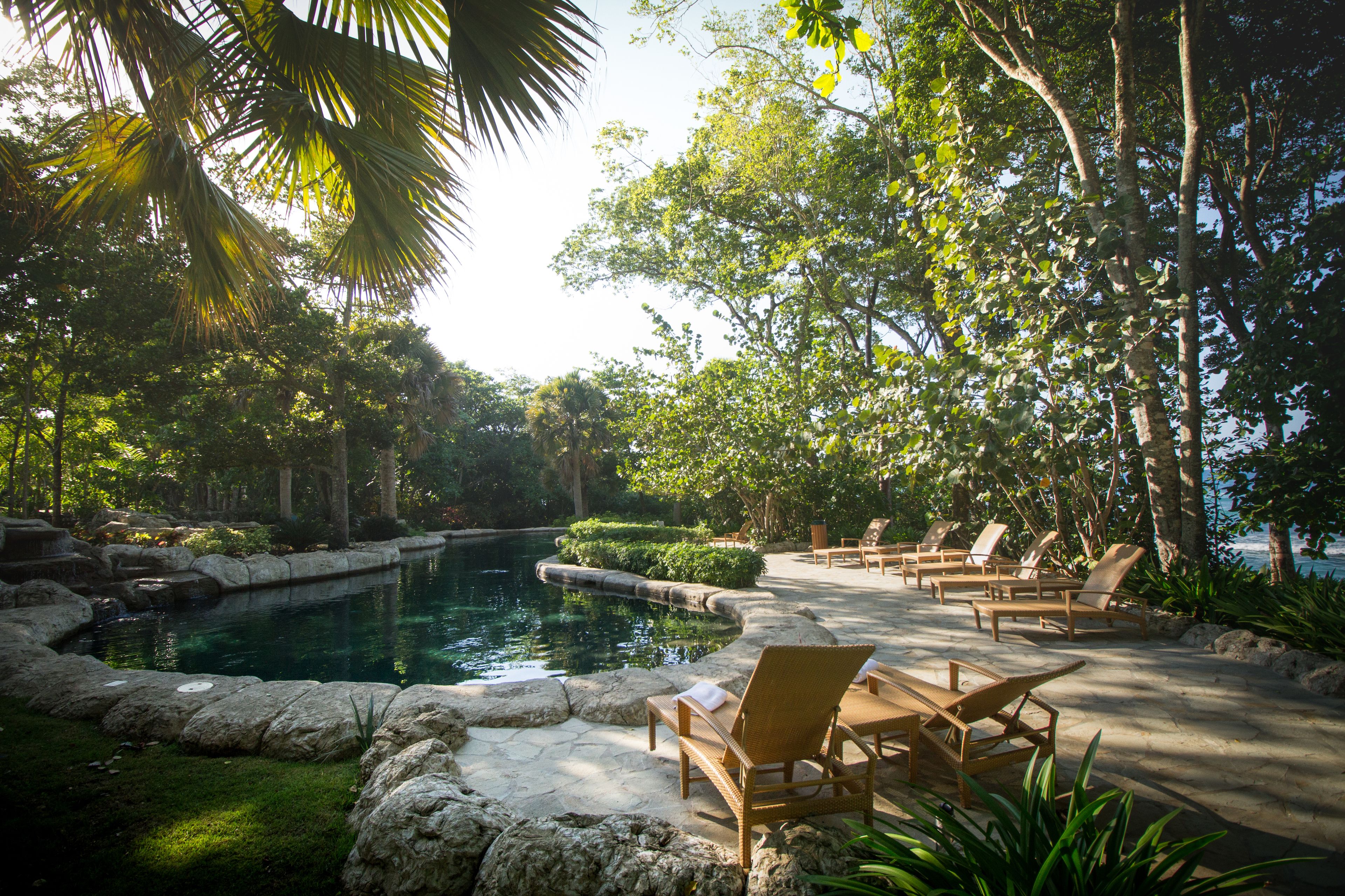 A serene outdoor pool area with lounge chairs and a stone pathway.