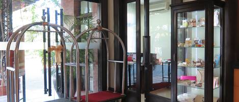 A hotel lobby with a business center sign, a glass display case with souvenirs, and a red carpeted trolley.