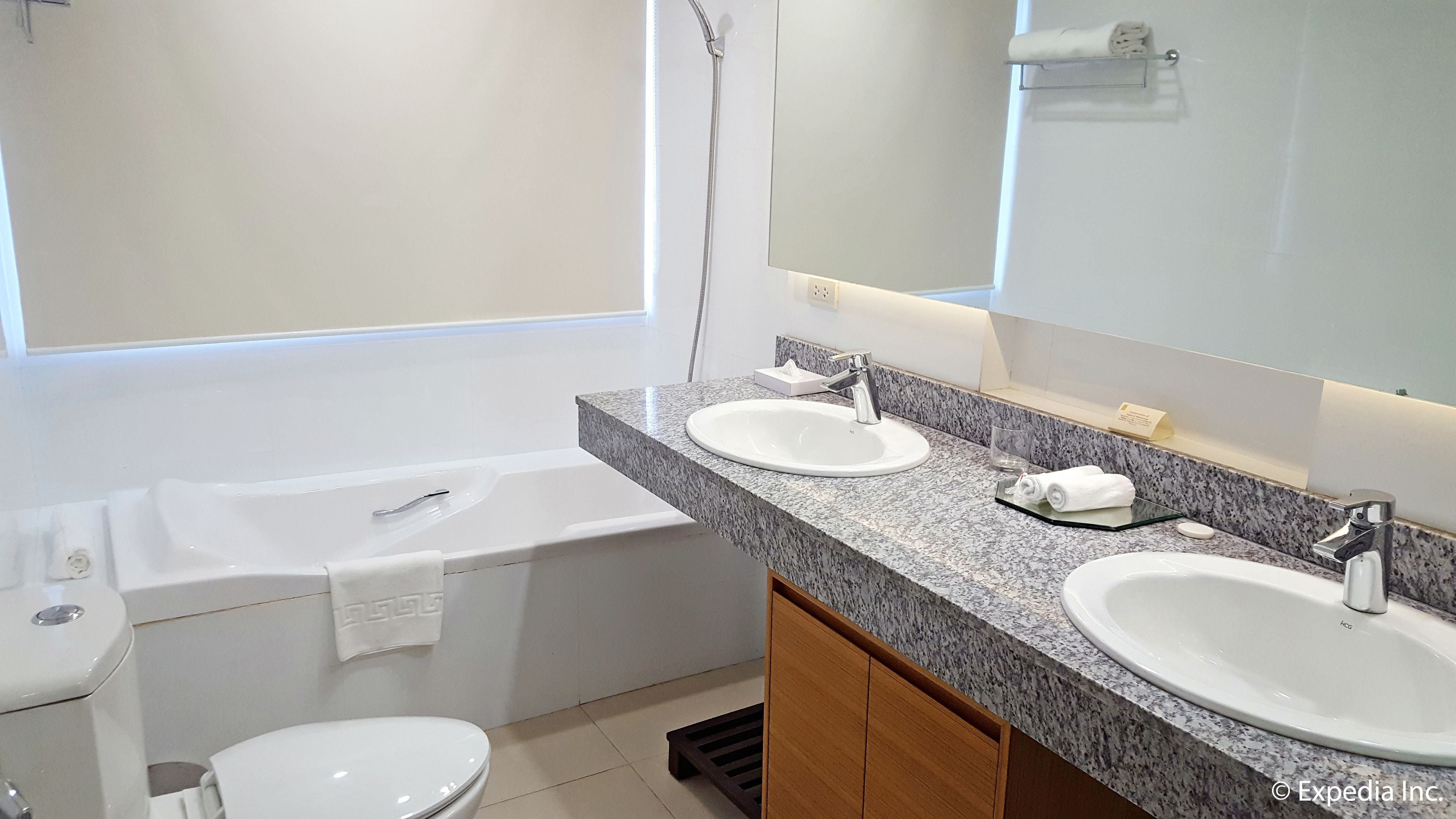 Un baño moderno con lavamanos doble, un espejo grande, una bañera y un inodoro.